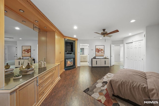 bedroom with ensuite bathroom, recessed lighting, a closet, a large fireplace, and dark wood-style flooring