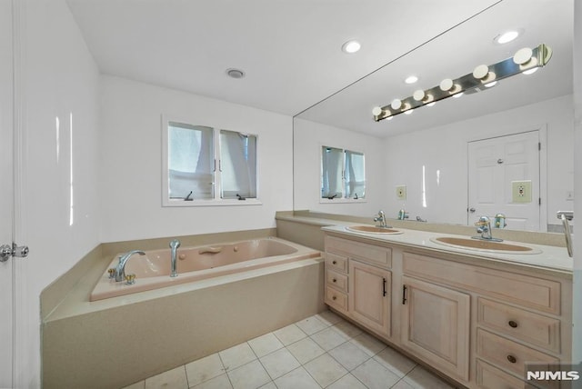 bathroom featuring tile patterned flooring, a garden tub, double vanity, and a sink