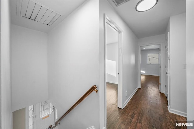 corridor with wood finished floors, an upstairs landing, visible vents, and baseboards