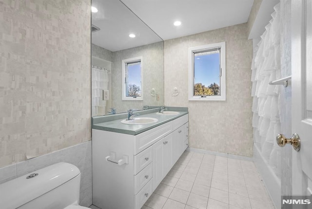 full bath featuring wallpapered walls, double vanity, toilet, and a sink