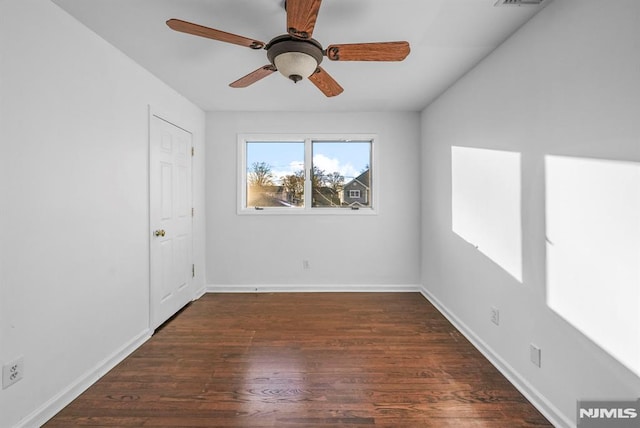 empty room with a ceiling fan, wood finished floors, and baseboards