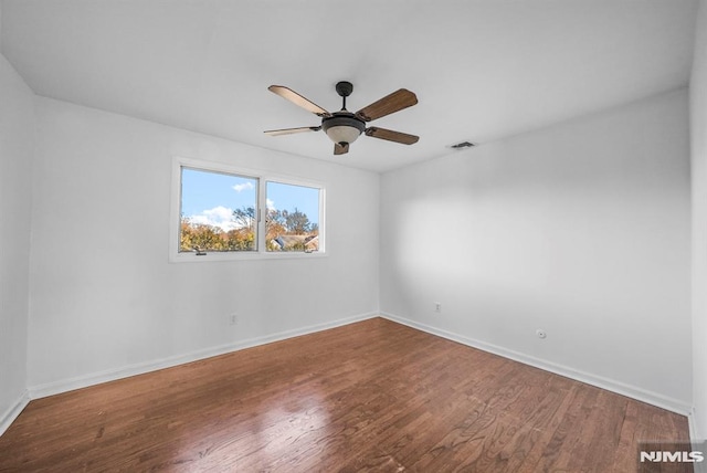 spare room featuring ceiling fan, visible vents, baseboards, and wood finished floors