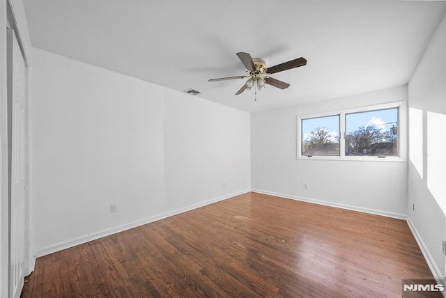 unfurnished room featuring ceiling fan, visible vents, baseboards, and wood finished floors