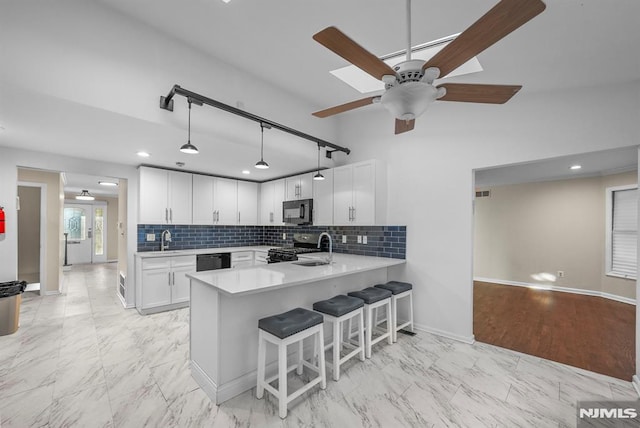 kitchen with light countertops, a kitchen breakfast bar, a peninsula, marble finish floor, and black appliances