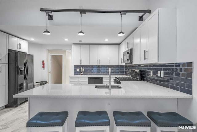 kitchen featuring black fridge, a peninsula, range, marble finish floor, and a sink