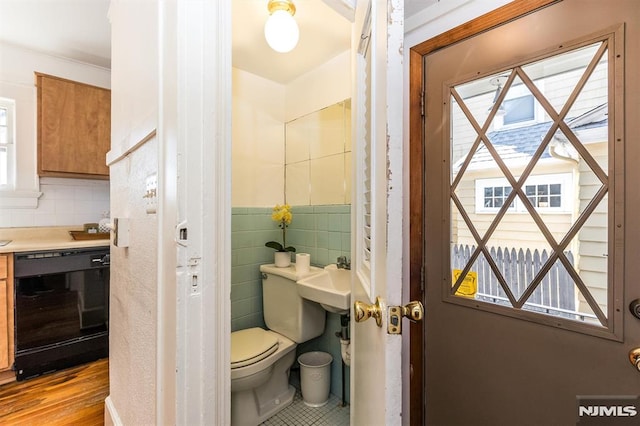 bathroom featuring toilet, tile walls, and a sink