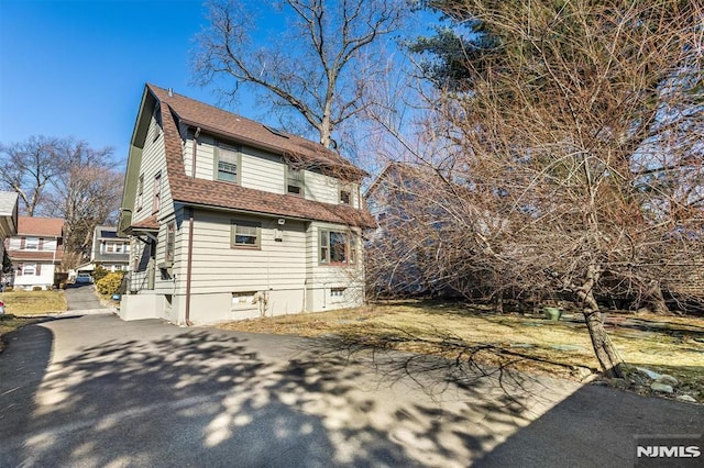 view of side of home featuring roof with shingles