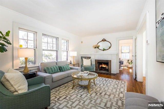 living area featuring a brick fireplace, dark wood-style floors, and crown molding