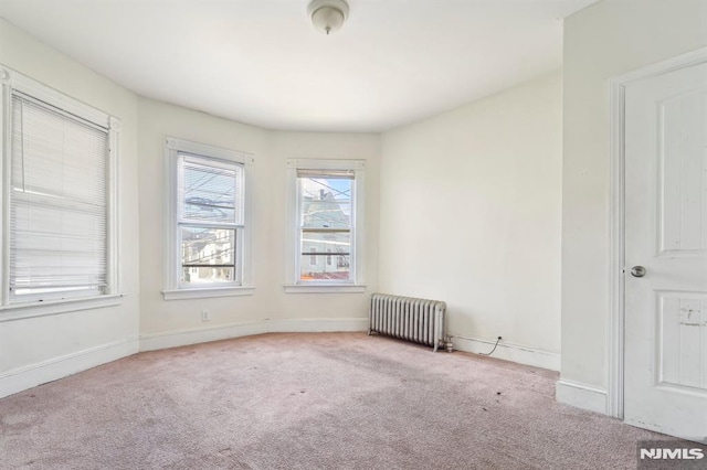 carpeted spare room with baseboards and radiator