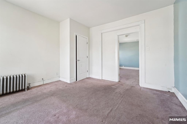 empty room featuring radiator, baseboards, and carpet floors