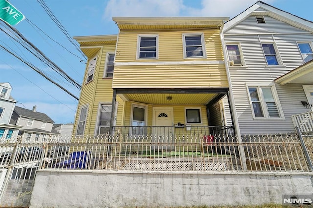 multi unit property with a fenced front yard and covered porch