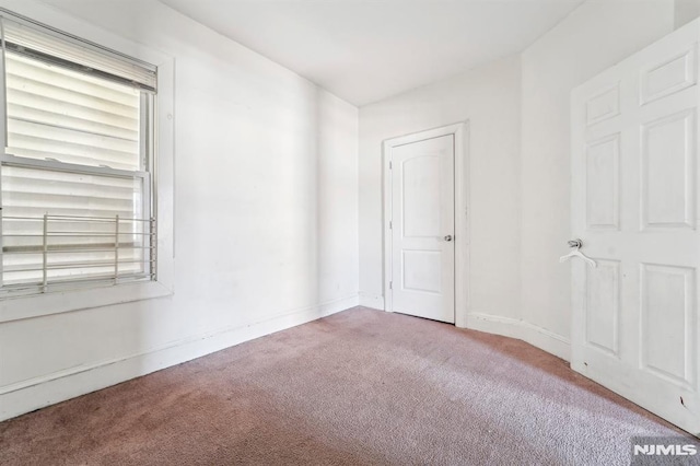 carpeted spare room featuring baseboards