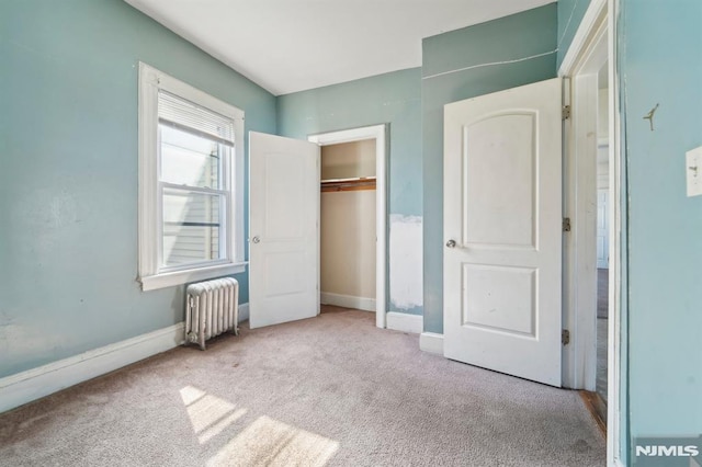 unfurnished bedroom with a closet, carpet flooring, radiator, and baseboards