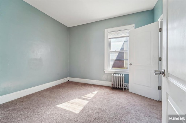 unfurnished room featuring baseboards, radiator, and carpet flooring