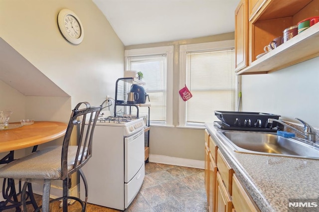 kitchen with baseboards, light countertops, lofted ceiling, white gas range, and a sink