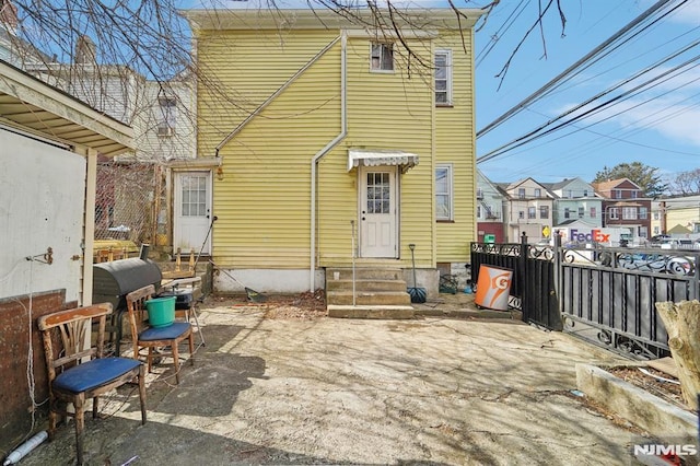 rear view of house featuring entry steps and fence