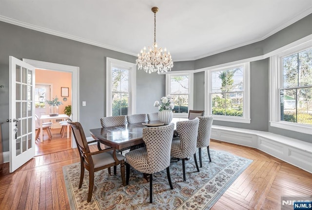 dining area with plenty of natural light, a notable chandelier, and crown molding