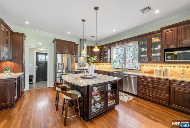 kitchen featuring visible vents, appliances with stainless steel finishes, wall chimney exhaust hood, and a healthy amount of sunlight