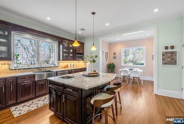 kitchen featuring backsplash, crown molding, a kitchen bar, and a sink