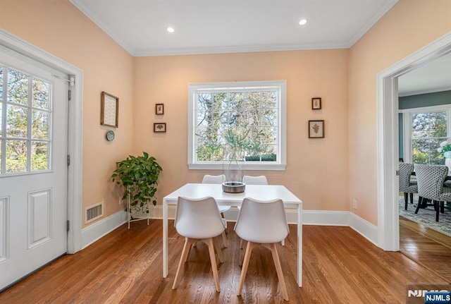 dining room with visible vents, ornamental molding, baseboards, and wood finished floors