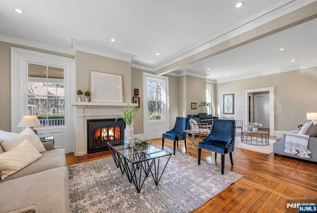 living area with recessed lighting, baseboards, a glass covered fireplace, and ornamental molding