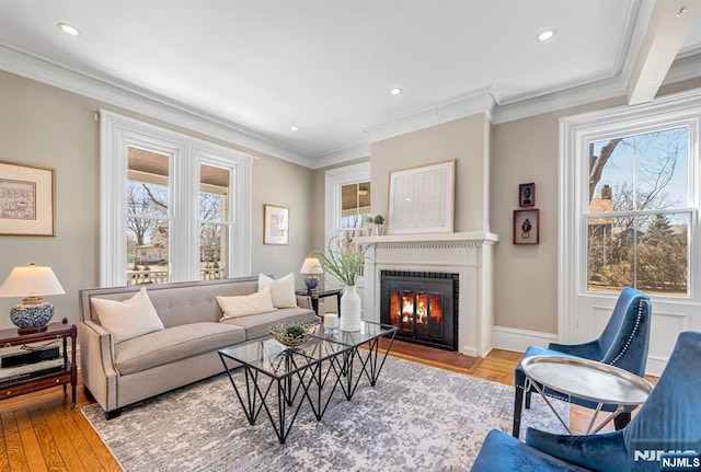 living room with baseboards, a fireplace with flush hearth, ornamental molding, recessed lighting, and wood finished floors