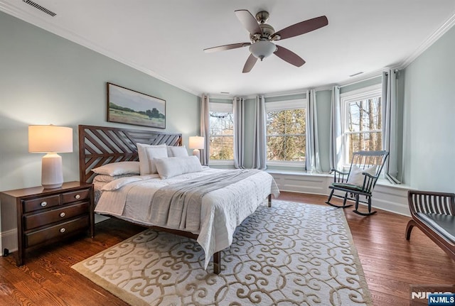 bedroom with a ceiling fan, baseboards, dark wood-style floors, visible vents, and ornamental molding