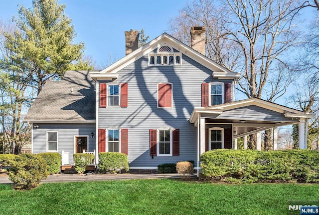 view of front of property featuring a shingled roof, a front lawn, and a chimney