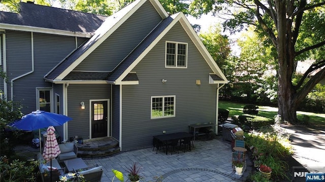 back of house featuring a patio and roof with shingles