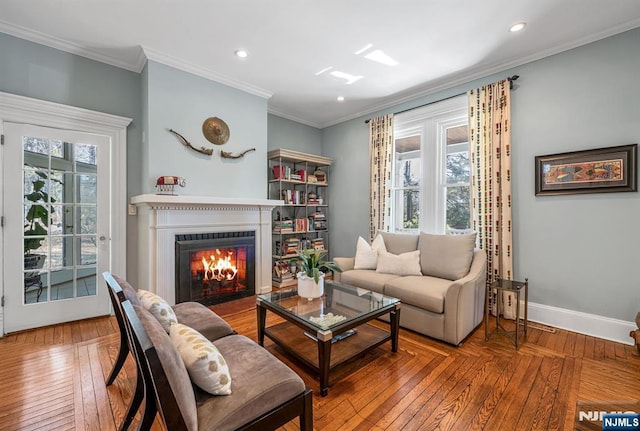 living room with hardwood / wood-style floors, baseboards, ornamental molding, and a fireplace with flush hearth