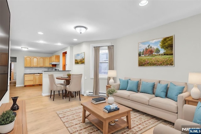 living room with baseboards, light wood-type flooring, lofted ceiling, recessed lighting, and a baseboard radiator