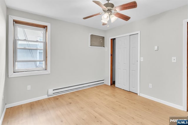 unfurnished bedroom with a baseboard heating unit, baseboards, light wood-type flooring, a closet, and a ceiling fan