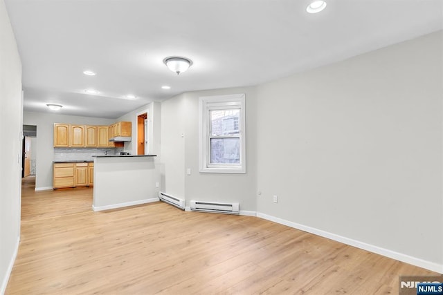 kitchen with under cabinet range hood, dark countertops, light wood-type flooring, and baseboard heating