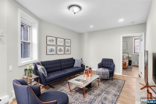 living room with recessed lighting, light wood-type flooring, baseboard heating, and a healthy amount of sunlight