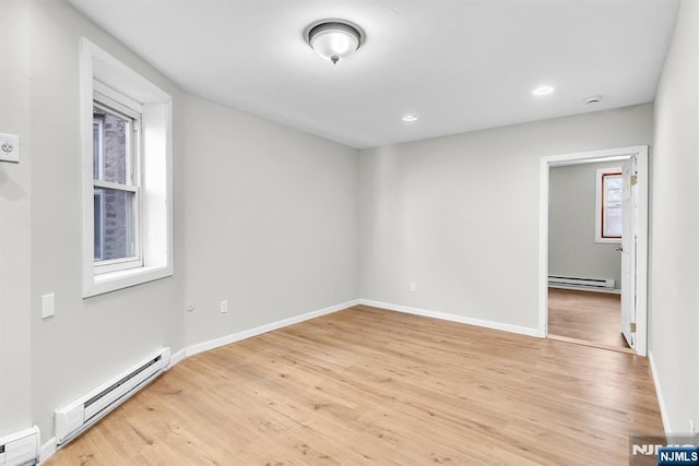 empty room featuring a baseboard heating unit and light wood-style floors