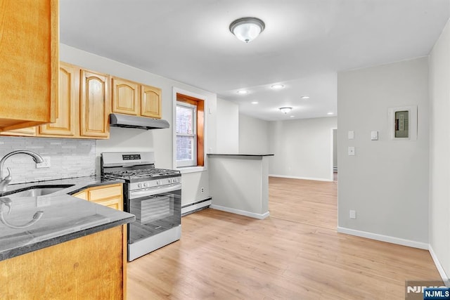 kitchen with backsplash, a baseboard heating unit, stainless steel range with gas cooktop, under cabinet range hood, and a sink