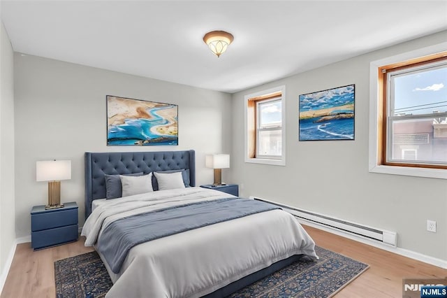 bedroom featuring a baseboard radiator, baseboards, and wood finished floors