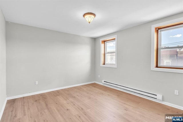 spare room with baseboards, baseboard heating, and wood finished floors