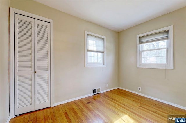 unfurnished bedroom with a closet, visible vents, light wood-style flooring, and baseboards