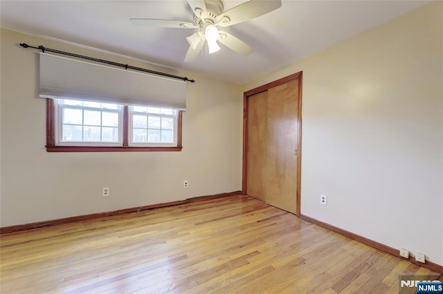 unfurnished bedroom featuring a closet, baseboards, light wood-style floors, and a ceiling fan