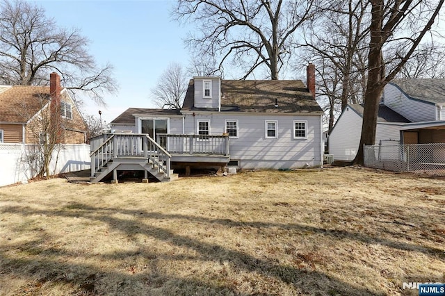 rear view of house with a wooden deck, a fenced backyard, a chimney, stairs, and a lawn