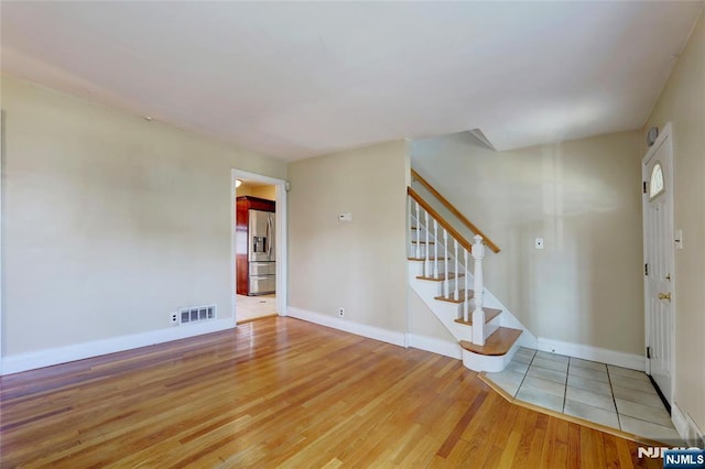 foyer featuring visible vents, stairway, baseboards, and wood finished floors