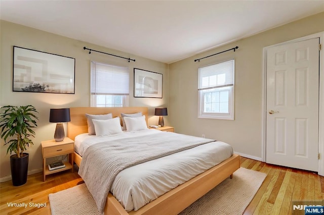 bedroom featuring light wood finished floors, multiple windows, and baseboards