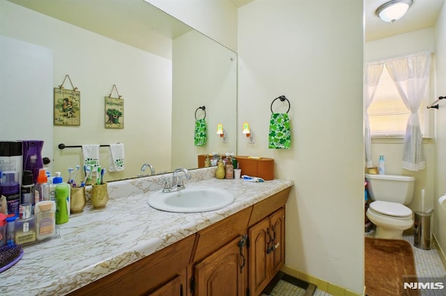 bathroom featuring tile patterned flooring, toilet, vanity, and baseboards