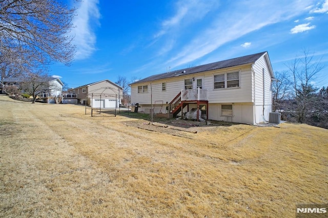 rear view of house featuring stairs, an outbuilding, central AC unit, and a lawn