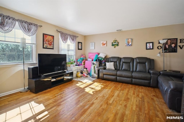 living room featuring visible vents, baseboards, and light wood-style flooring