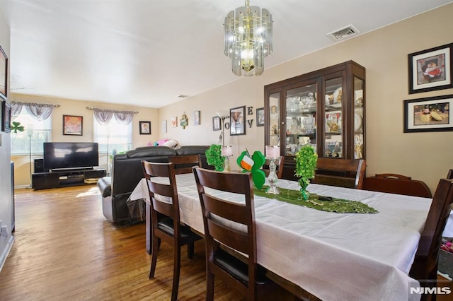 dining space with a notable chandelier, wood finished floors, and visible vents