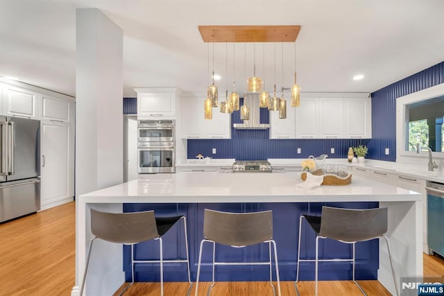 kitchen featuring light countertops, white cabinets, light wood-style flooring, and stainless steel appliances