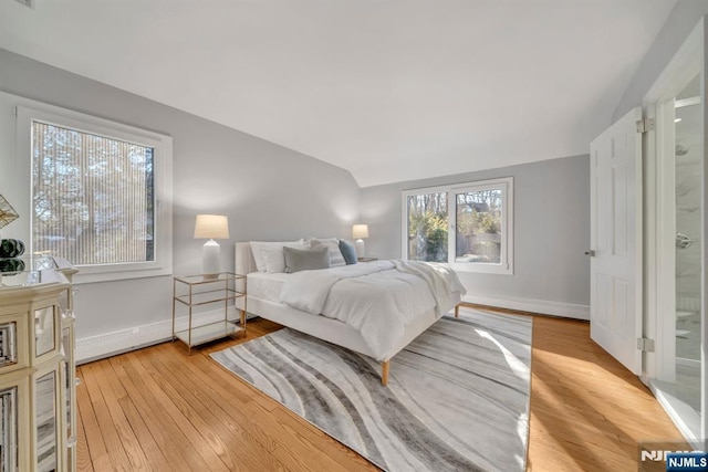 bedroom featuring baseboards, lofted ceiling, and light wood finished floors