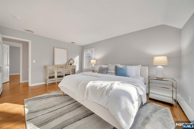 bedroom with visible vents, baseboards, lofted ceiling, and wood finished floors